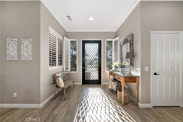 foyer entrance with baseboards, visible vents, crown molding, and wood finished floors