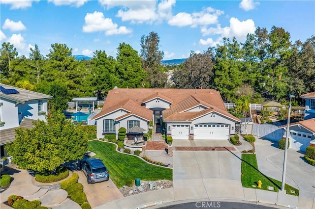 view of front of house featuring driveway, a garage, a tile roof, a gate, and fence