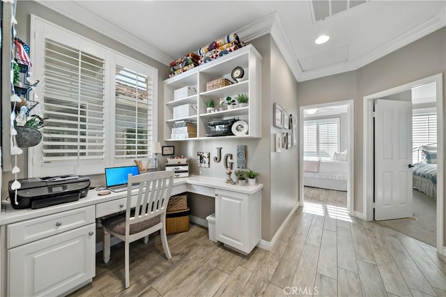 office space with light wood-style flooring, crown molding, built in desk, and baseboards