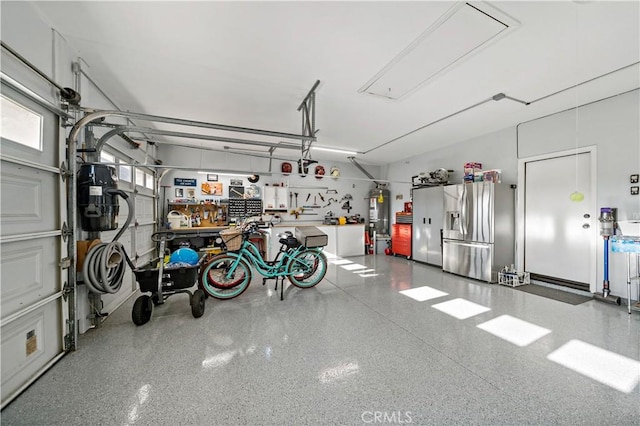 garage with strapped water heater, a workshop area, and stainless steel fridge with ice dispenser