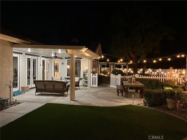 patio at twilight featuring outdoor lounge area, fence, and a pergola