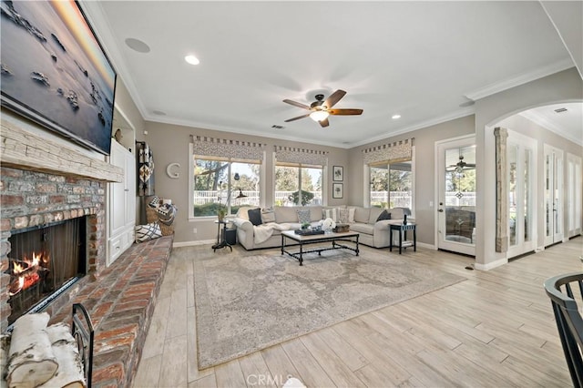 living room with ceiling fan, a fireplace, baseboards, and wood finished floors