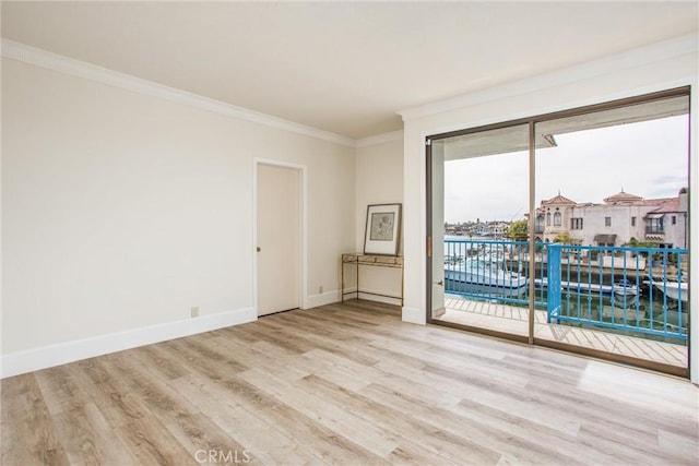 empty room featuring baseboards, wood finished floors, and crown molding