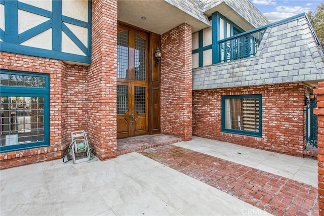 property entrance featuring french doors, brick siding, and a balcony