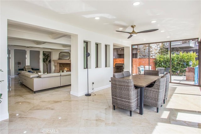 dining space with marble finish floor, recessed lighting, a ceiling fan, a warm lit fireplace, and baseboards