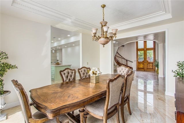 dining space with baseboards, arched walkways, a raised ceiling, marble finish floor, and a chandelier