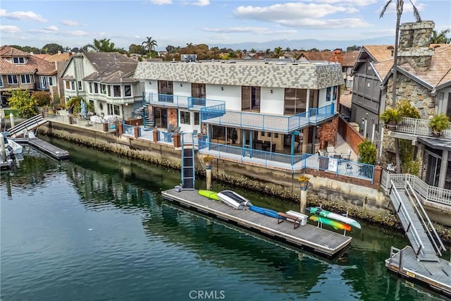 back of house with a water view, a balcony, and a residential view