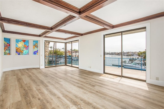 empty room with beam ceiling, coffered ceiling, and light wood-style flooring