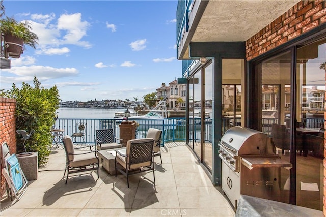 view of patio / terrace featuring a water view, a grill, and an outdoor kitchen