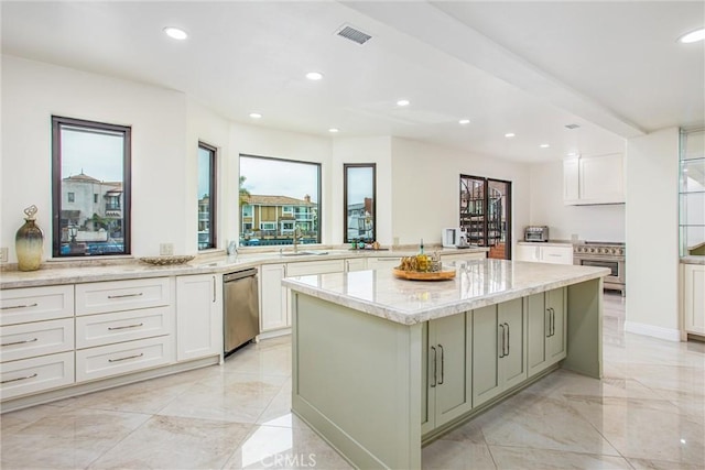 kitchen with wall oven, a healthy amount of sunlight, light stone counters, and a center island