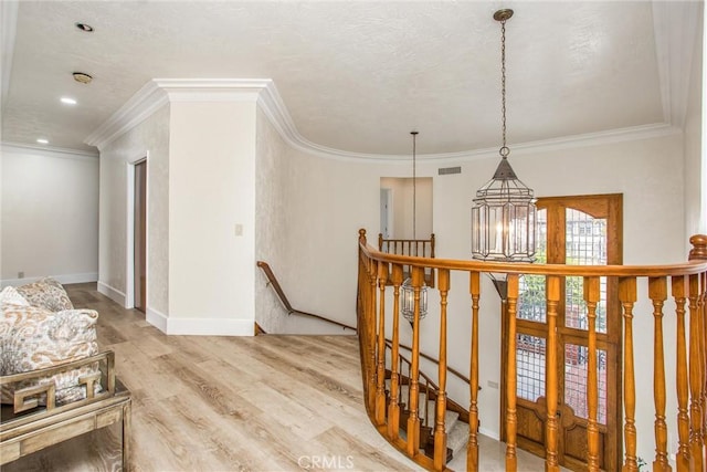 corridor with crown molding, visible vents, an upstairs landing, wood finished floors, and baseboards