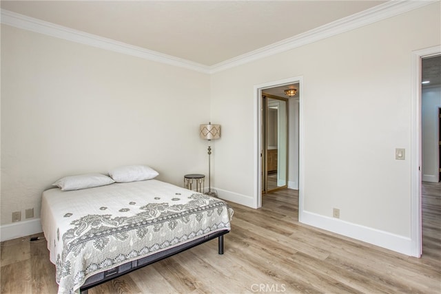 bedroom with light wood-style floors, crown molding, and baseboards