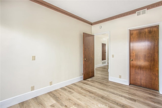 unfurnished bedroom with ornamental molding, baseboards, visible vents, and light wood finished floors