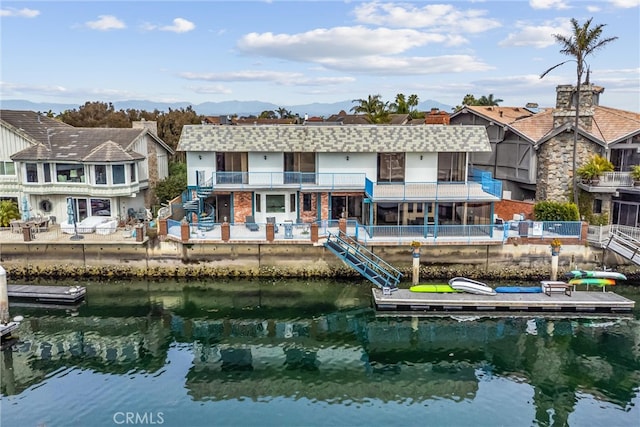 rear view of property featuring a water view and a balcony