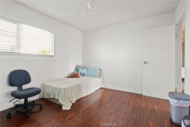 bedroom with a textured ceiling, baseboards, and wood finished floors