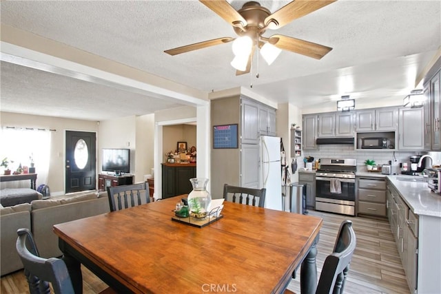 dining space featuring ceiling fan, a textured ceiling, and light wood finished floors