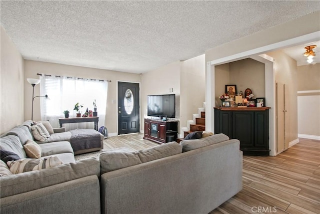 living area with stairway, baseboards, a textured ceiling, and light wood finished floors