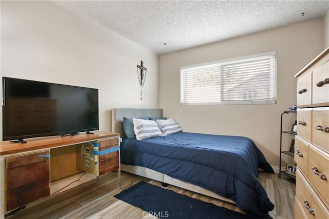 bedroom with a textured ceiling and wood finished floors