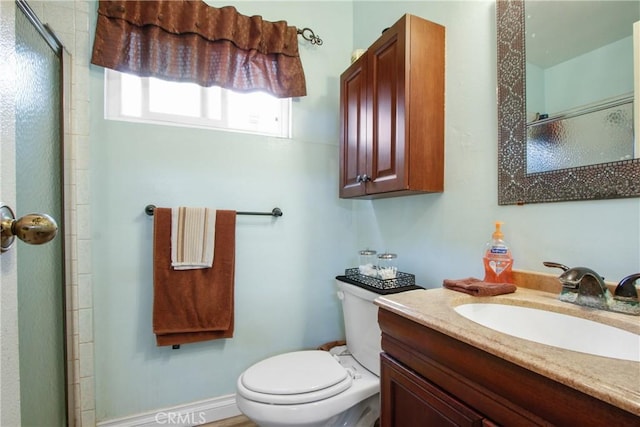 full bathroom featuring a shower with shower door, vanity, and toilet