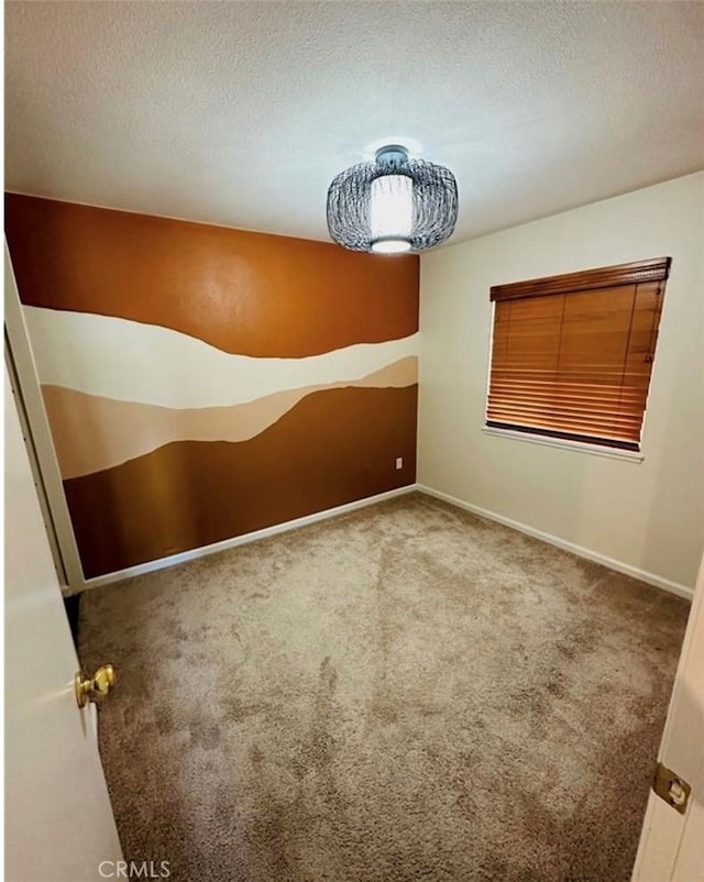 spare room with carpet floors, a textured ceiling, and baseboards