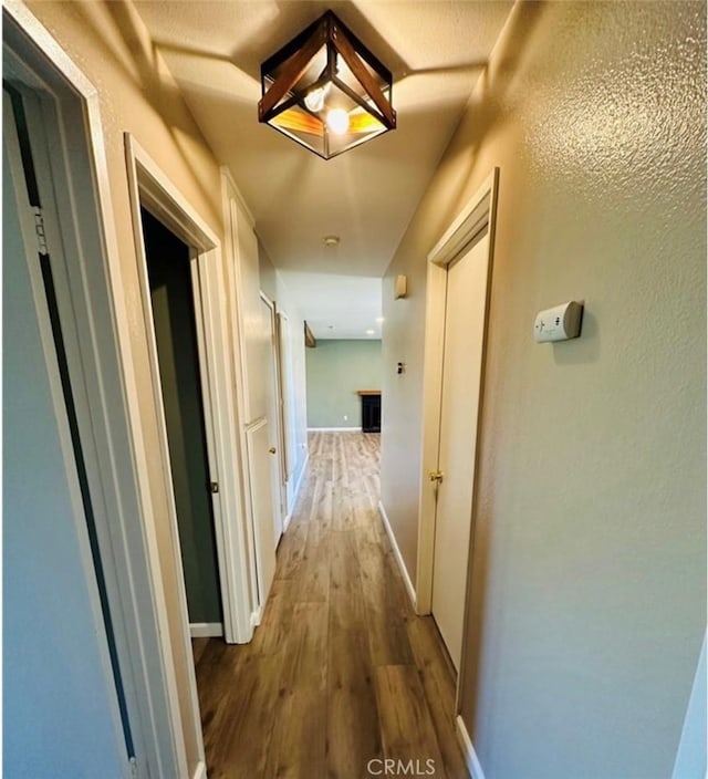 corridor with wood finished floors and baseboards