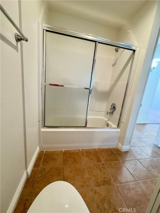 bathroom featuring enclosed tub / shower combo, tile patterned flooring, and baseboards