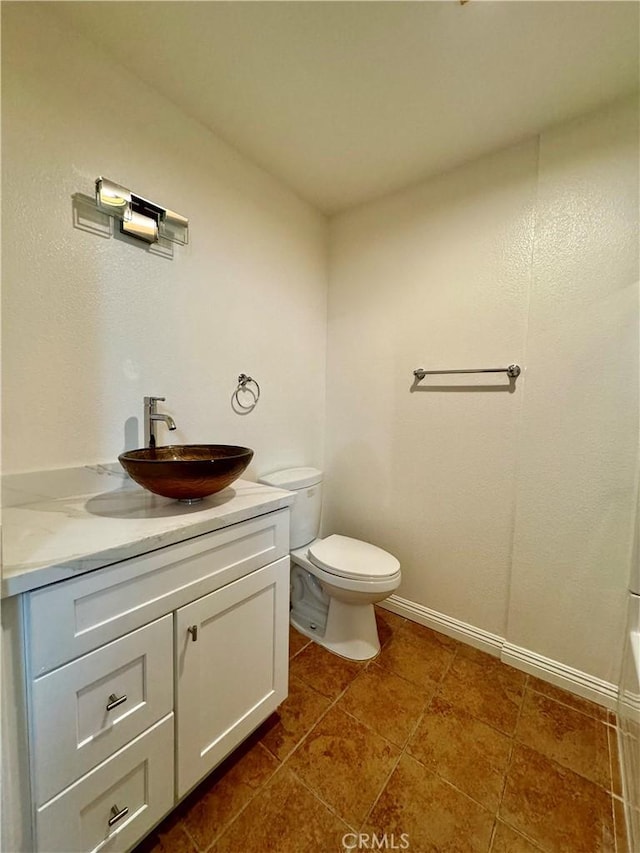 full bathroom featuring a bathtub, vanity, toilet, and baseboards