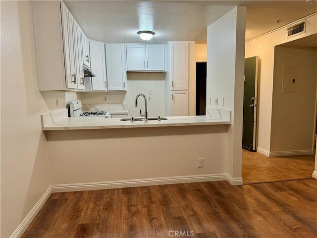 kitchen with light countertops, visible vents, white range with gas cooktop, a sink, and a peninsula