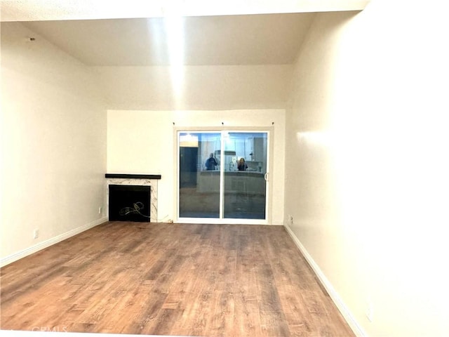 unfurnished living room with a fireplace, baseboards, and wood finished floors