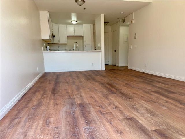 kitchen with light countertops, a sink, baseboards, and wood finished floors