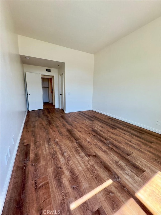 spare room with baseboards, visible vents, and wood finished floors