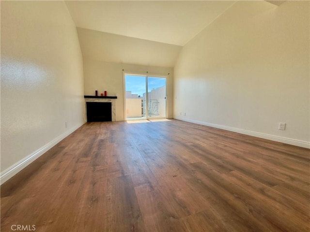 unfurnished living room with lofted ceiling, a fireplace, baseboards, and wood finished floors