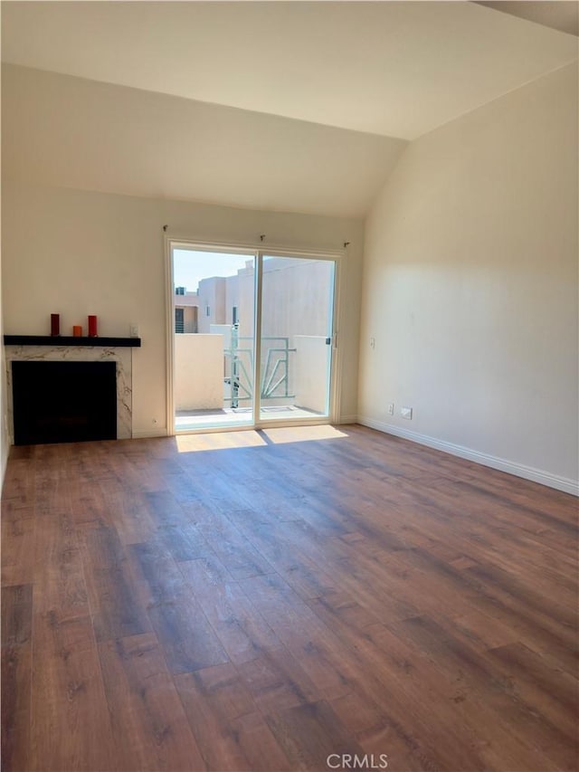 unfurnished living room featuring lofted ceiling, baseboards, and wood finished floors