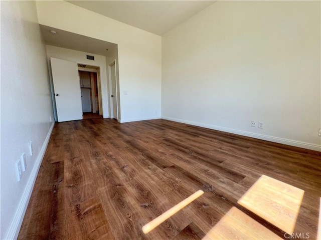 unfurnished room featuring visible vents, baseboards, and wood finished floors