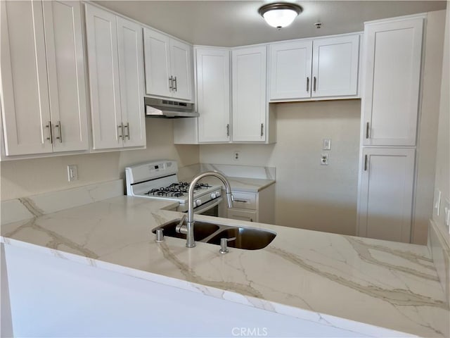 kitchen featuring white range with gas stovetop, white cabinets, under cabinet range hood, and light stone countertops