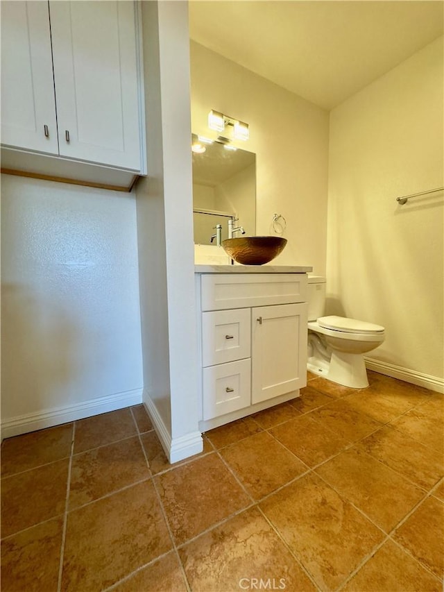 bathroom featuring toilet, vanity, baseboards, and tile patterned floors