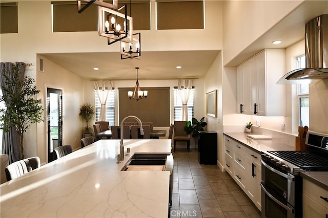 kitchen with decorative light fixtures, an inviting chandelier, double oven range, white cabinetry, and a sink