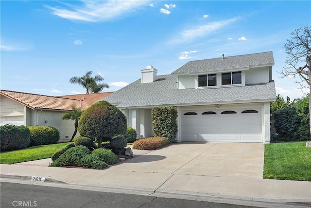 traditional-style home featuring concrete driveway, a chimney, and an attached garage