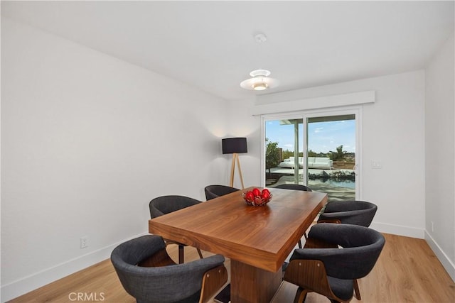 dining space with light wood-style flooring and baseboards