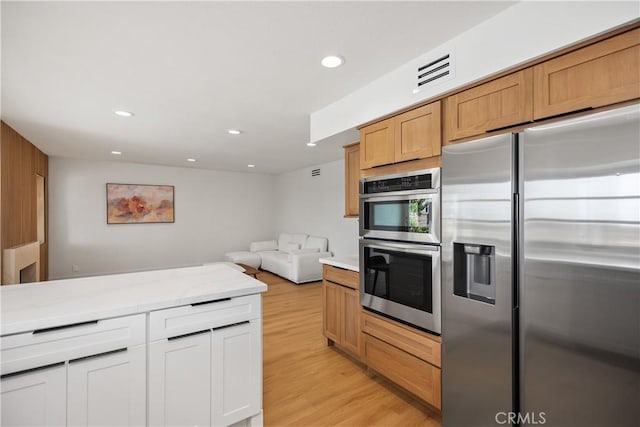 kitchen featuring stainless steel appliances, recessed lighting, visible vents, open floor plan, and light wood-type flooring