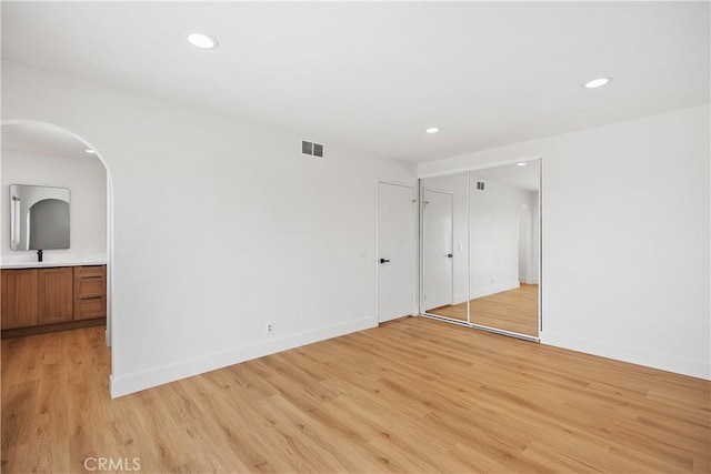 empty room featuring baseboards, light wood finished floors, visible vents, and recessed lighting