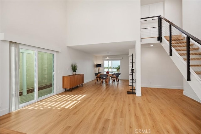 foyer with stairs, a high ceiling, baseboards, and wood finished floors