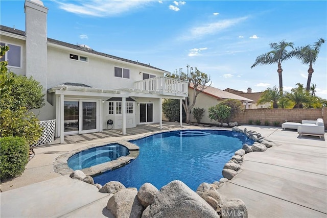 view of pool with a patio, fence, and a pool with connected hot tub