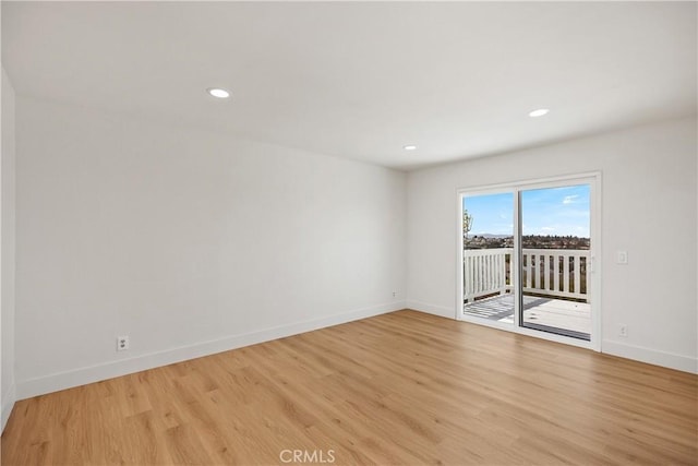 empty room with light wood-type flooring, baseboards, and recessed lighting