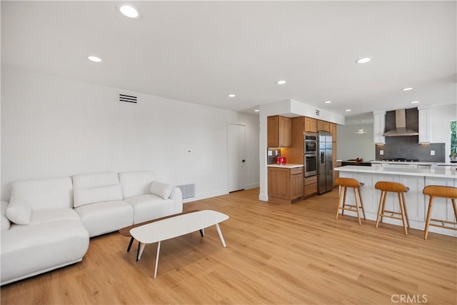 living room featuring light wood-type flooring, visible vents, and recessed lighting