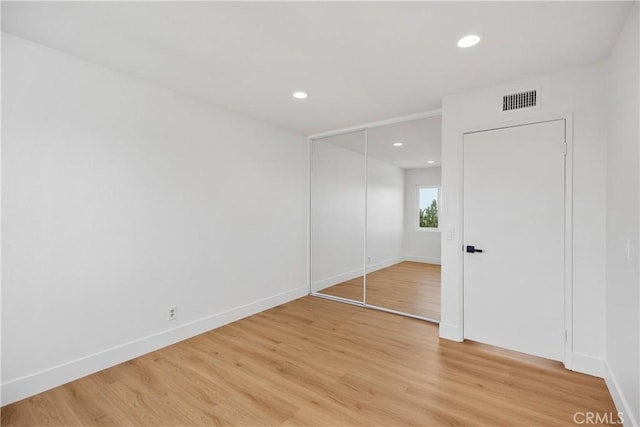 unfurnished bedroom with recessed lighting, a closet, visible vents, light wood-style flooring, and baseboards