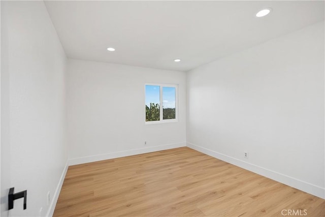 spare room featuring recessed lighting, light wood-type flooring, and baseboards