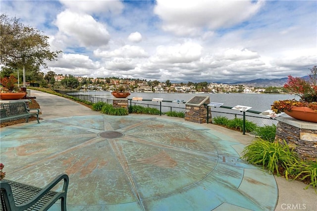 view of patio / terrace featuring a water view and fence