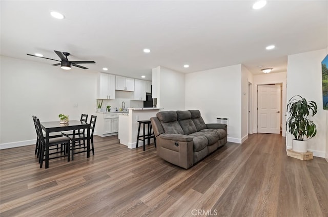 living room featuring baseboards, wood finished floors, and recessed lighting