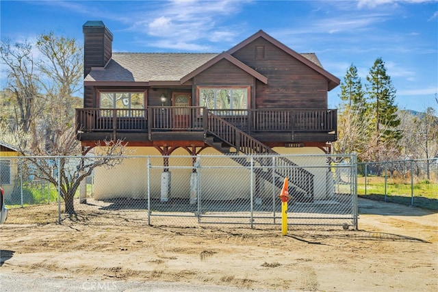 chalet / cabin featuring a shingled roof, stairway, a chimney, and fence